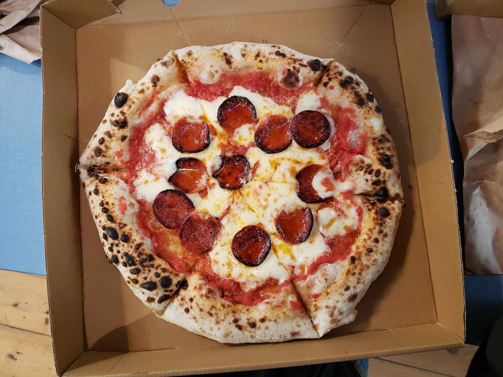 Pepperoni pizza with a charred crust in an open takeout box